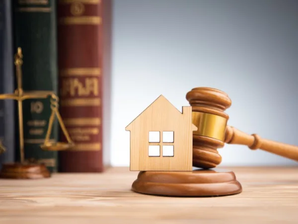 Représentation d'une maison en bois sur un marteau de juge, symbolisant les litiges liés au logement.