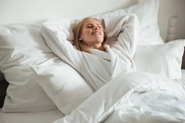 Femme heureux dans un lit d'hôtel.