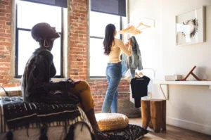 Deux femmes dans un appartement lumineux, l'une regarde des vêtements.