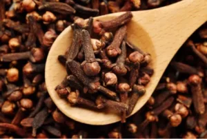 Clous de girofle sur une cuillère en bois pour des solutions naturelles.